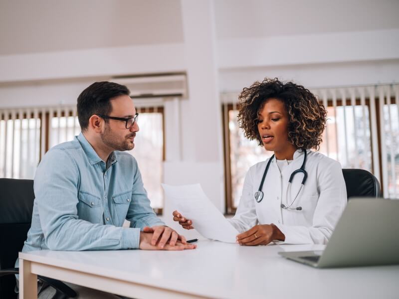 Image of a male medical management specialist speaking to a primary care physician.